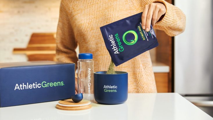 Athletic Greens powder being mixed into cup of water by woman